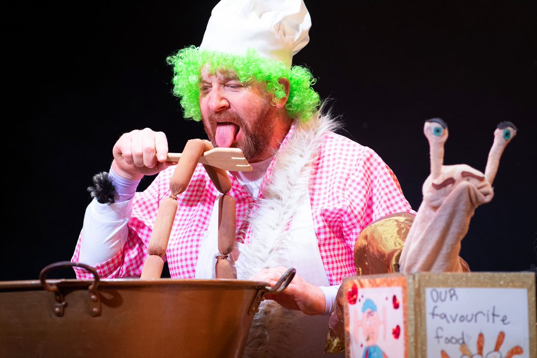 actor performing as troll character tasting his baking mixture on stage