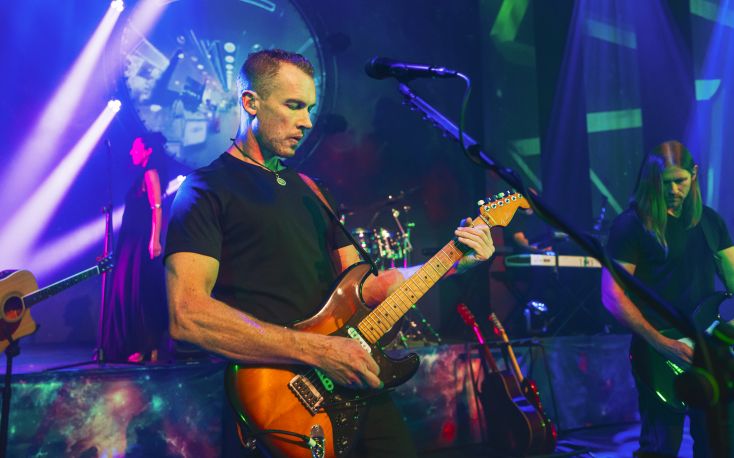 A man plays guitar bathed in blue light.